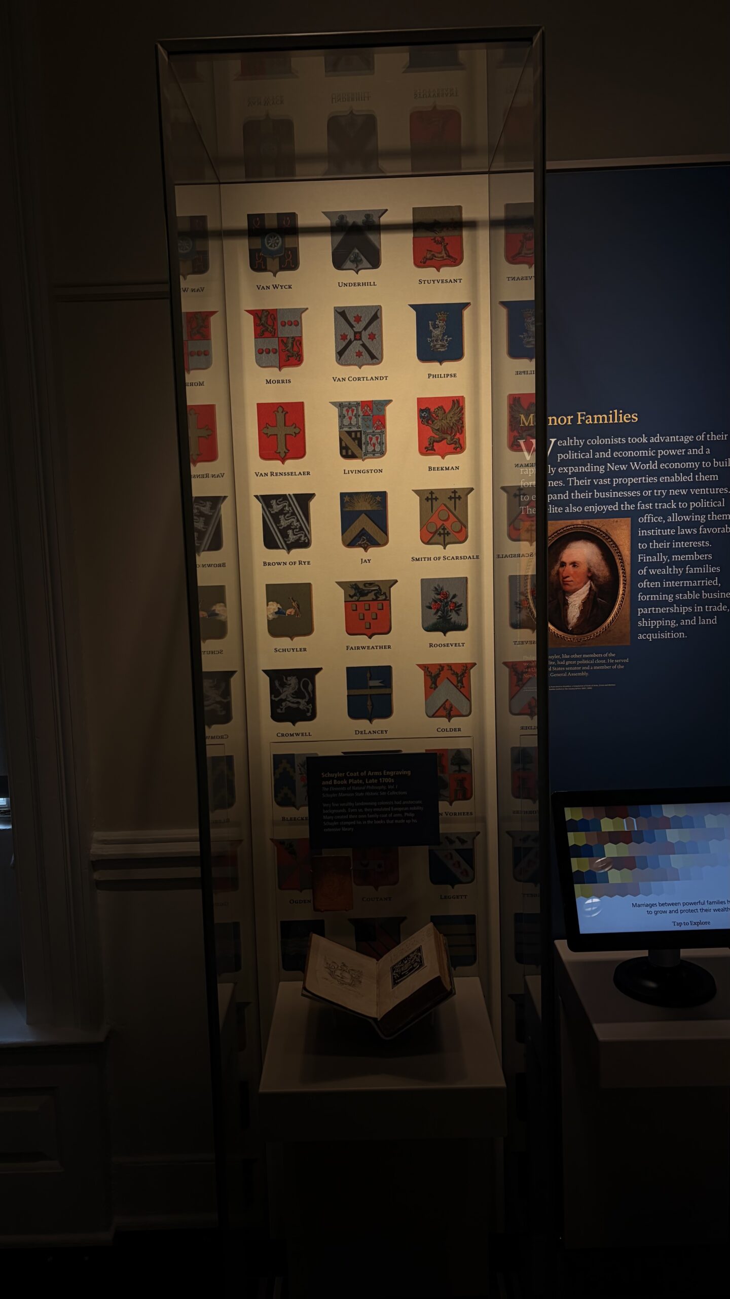 Tall museum exhibit panel titled Manor Families, with a portrait and an interactive monitor below