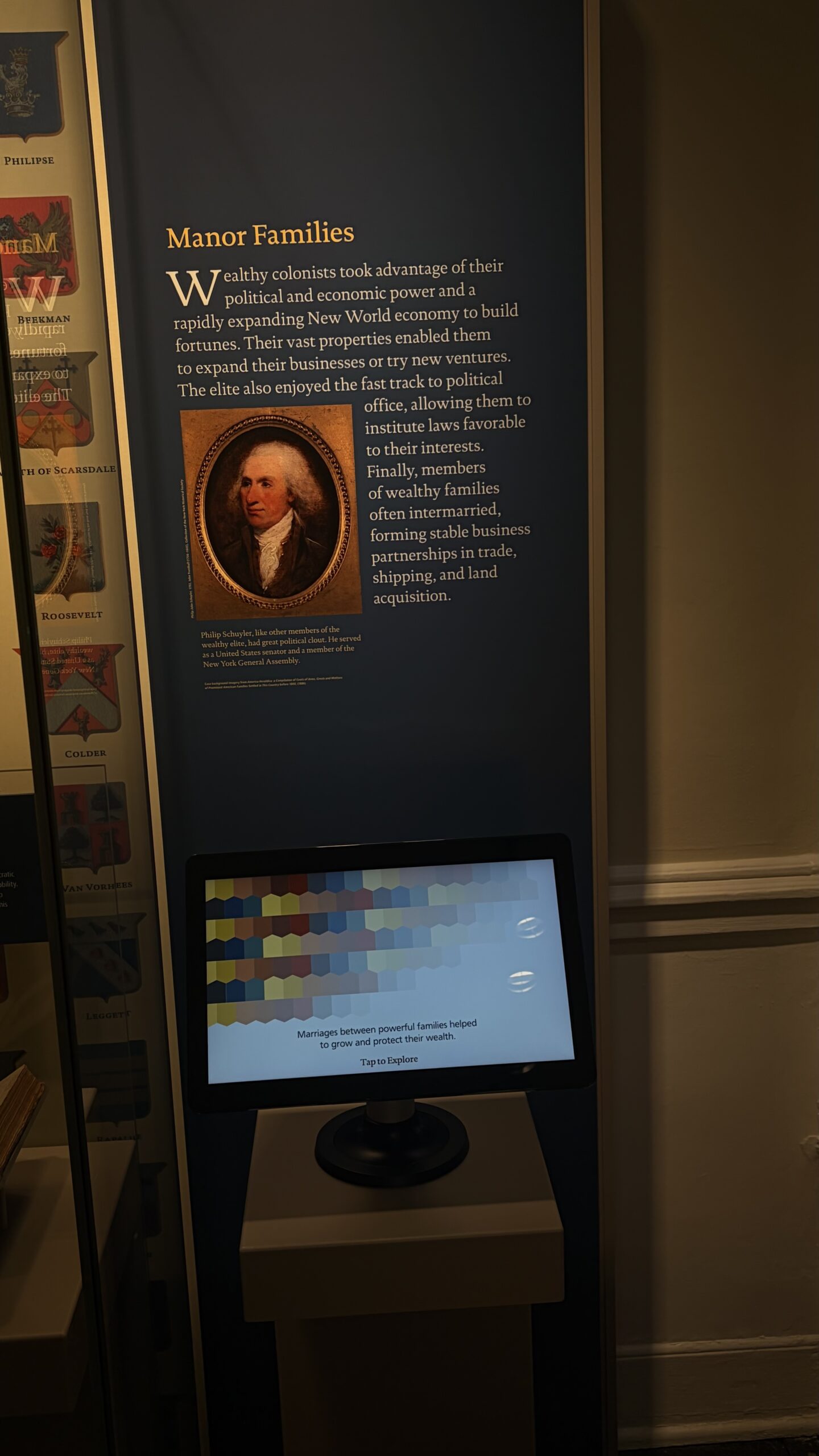Museum gallery view with heraldic panels, the Manor Families exhibit, and an interactive monitor
